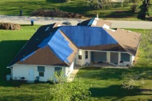 Roof Leak. Roof Damaged House Rooftop Covered With Protective Plastic Tarp.