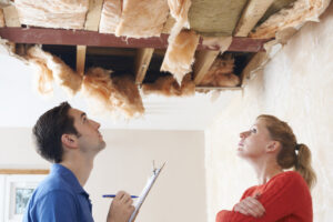 Roof Leak Repair. Builder And Client Inspecting Roof Damage.