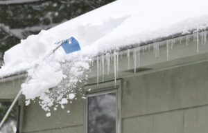 Winter Roof Damage. Removing Snow On The Roof After Snow Storm.